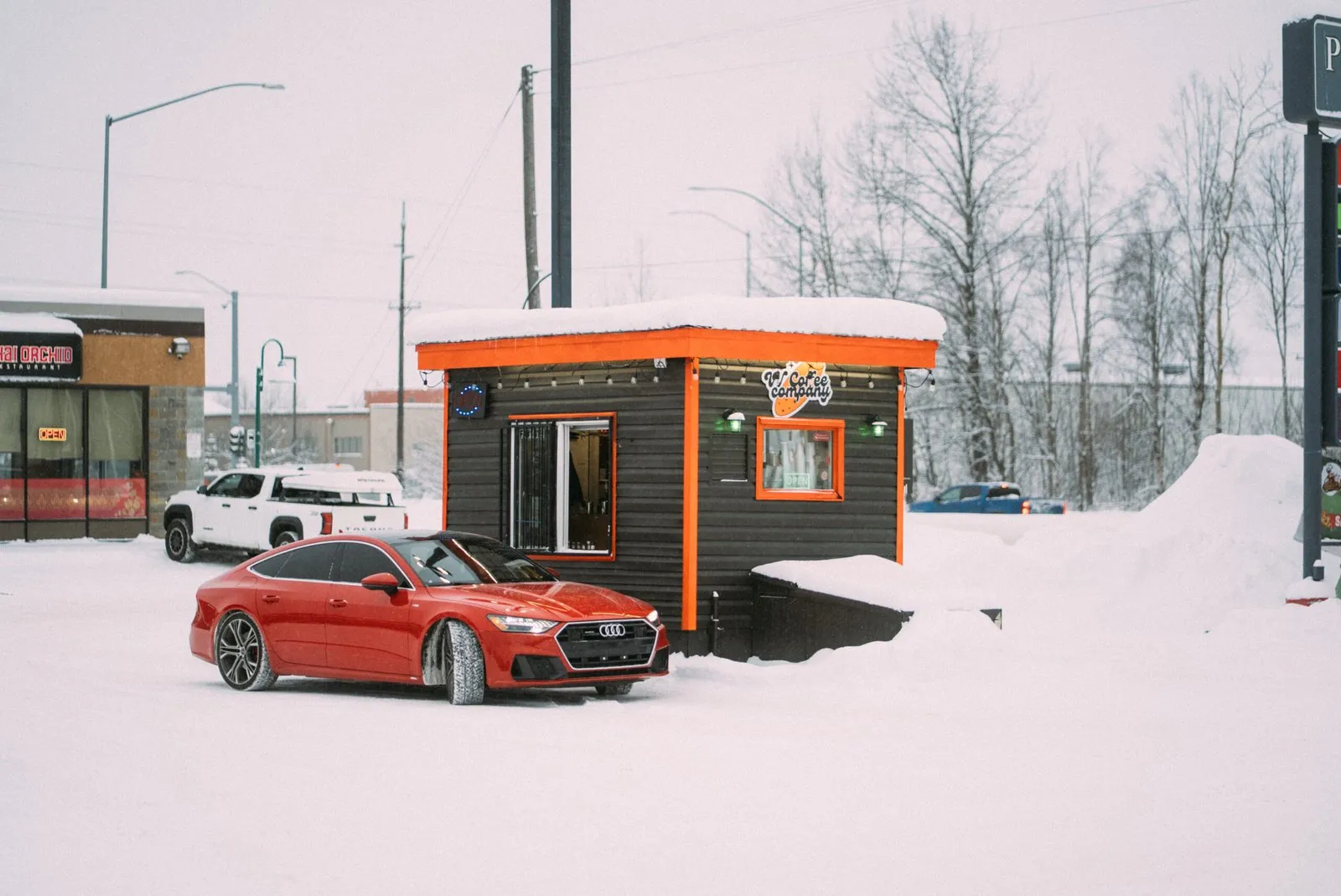 VV's Coffee drive-thru hut with orange trim in the snow, a red Audi pulled up to the window